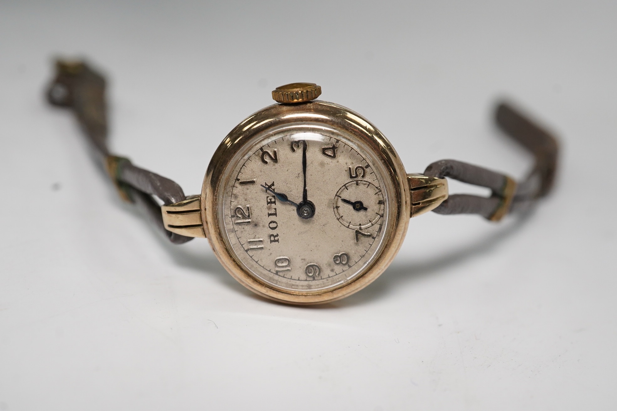 A lady's 9ct gold Rolex manual wind wrist watch, with Arabic dial and subsidiary seconds, case back numbered 22110, case diameter 21mm, on an associated twin strand fabric strap. Condition - poor to fair